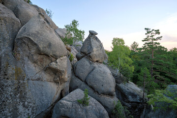 Huge rocky boulder formations high in mountains with growing trees on summer sunny day