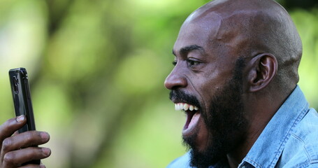 Man excited to good news on cellphone, middle aged african ethnicity