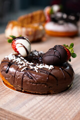 Donut dessert decorated with strawberry and chocolate sauce. Side view