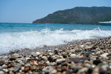 Waves and colored stones breaking on the shore with sea foam.The murky sea, the boat and the...