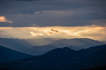 Panoramic view during sunset from Meteora rocks to Pindos mountains, the biggest mountain range of Greece, Thessaly district, Greece, Europe. Soft sun beam through clouds reaching the summit tops