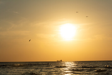 Sunset over the sea with a ship on the horizon