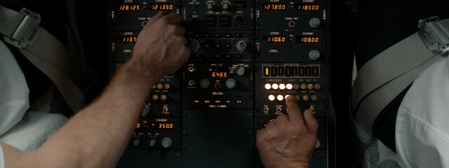 CU Commercial aircraft pilots adjusting radio channel parameters during the flight at high altitude. View from inside the cabin. Real aircraft, daytime shot