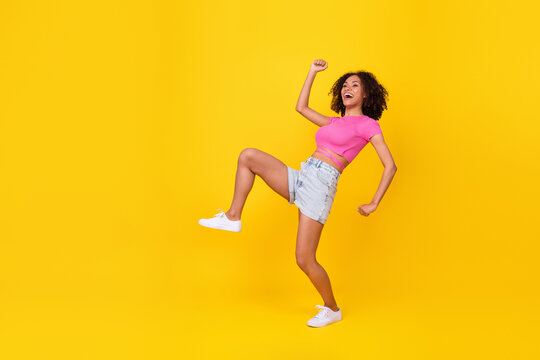 Full length portrait of excited carefree lady dance sneaky walking look empty space isolated on yellow color background