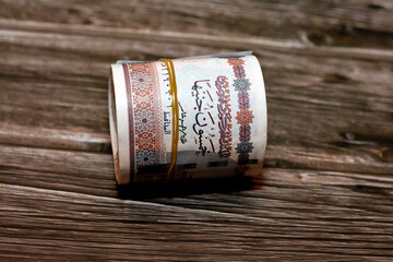 Egypt money roll pounds isolated on wooden background, 50 LE fifty Egyptian pounds cash money bills rolled up with rubber bands with a image of Abu Hurayba Mosque, temple of Edfu and winged scarab - obrazy, fototapety, plakaty