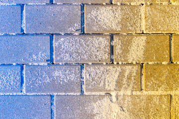 blue-yellow hailstone superimposed on stacked paving slabs sprinkled with sand, selective focus