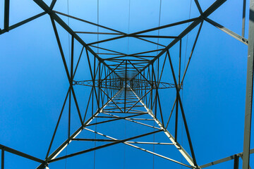Electricity pylon for over land power transmission of high voltage in front of blue sky