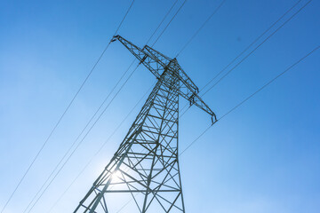 Electricity pylon for over land power transmission of high voltage in front of blue sky