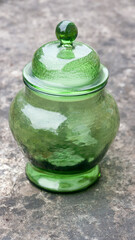Vasija de cristal verde con tapa sobre mesa de piedra