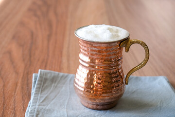 Ayran - Buttermilk. Traditional Turkish yoghurt drink with foam in a copper metal cup. Copy space for text