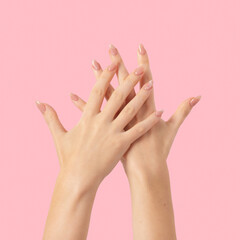 Hands of a beautiful well-groomed with feminine beige nude marble design nails gel polish on a pink background. Manicure, pedicure beauty salon concept.