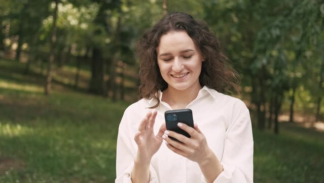 footage of young cheerful woman swiping smartphone in free time.