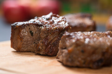 Closeup of grilled meat chunks served on wooden board