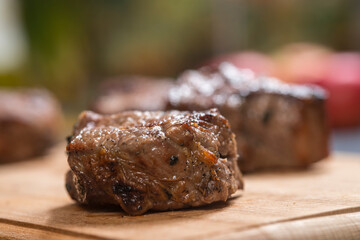 Closeup of grilled meat chunks served on wooden board