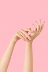 Hands of a beautiful well-groomed with feminine beige nude marble design nails gel polish on a pink...