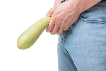 Man crop view holding zucchini as penis at crotch level imitating erectile dysfunction