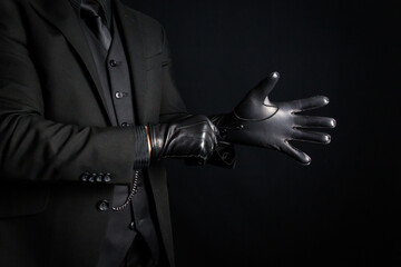 Portrait of Strong Man in Dark Suit Pulling on Black Leather Gloves. Concept of Mafia Hitman or Criminal Violence.