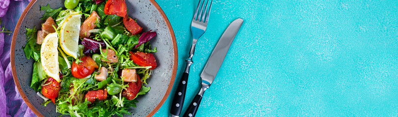 Fresh salad with salmon fish mixed with greens, tomato, olives, mustard and lemon juice
