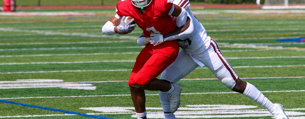 Football receiver trying to escape a tackle after catching the ball during a game