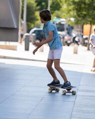 Young active elegant stylish kid balancing on a skateboard in Madrid city centre
