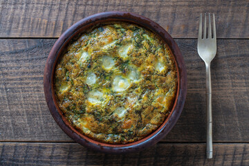 Ceramic bowl with vegetable frittata. Frittata with eggs, green beet leaves, onion, pepper, spices and cheese