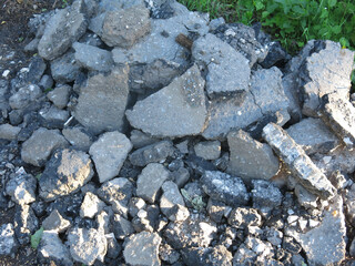 pieces of old removed broken asphalt are lying around in a heap