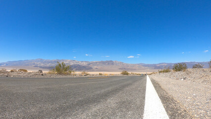 State Route 190 crossing Panamint Valley in Death Valley National Park, California, United States. Empty desert road in Death Valley with clear blue sky.