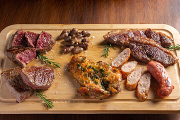 Picanha, traditional cut of Brazilian meat, chicken hearts , boneless chicken thigh and sausage served on a wooden board