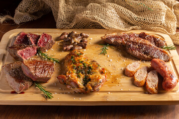 Picanha, traditional cut of Brazilian meat, chicken hearts , boneless chicken thigh and sausage served on a wooden board