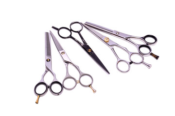 A set of silver hairdressing scissors for cutting and thinning hair with old black scissors in the center. Isolated on a white background. Professional barber tool