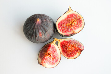 Photo of a fig close-up on a white background. Ripe fruit whole and in pieces.