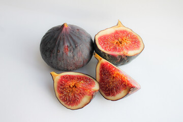 Photo of a fig close-up on a white background. Ripe fruit whole and in pieces.