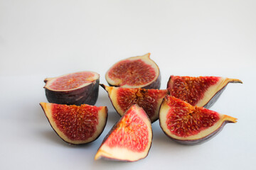 Photo of a fig close-up on a white background. Ripe fruit whole and in pieces.