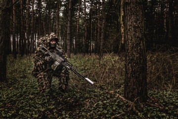 Eastern special forces soldier with rifle in woodland during autumn - 532517171