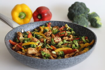 Stir fried vegetables with chicken in frying pan. Air fried chicken cubes tossed with sauteed bell peppers and broccoli.