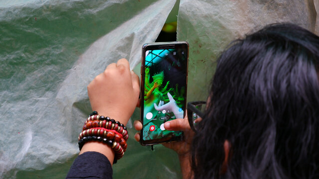 Girl taking picture of maa durga in rain from the hole in plastic.