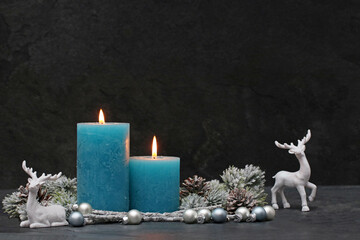 Christmas background: Turquoise candles in the snow with Christmas decorations.