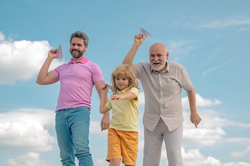 Three generations of men together, portrait of smiling son, father and grandfather with a toy airplane. Child boy playing with plane and dreaming future. Old and young.