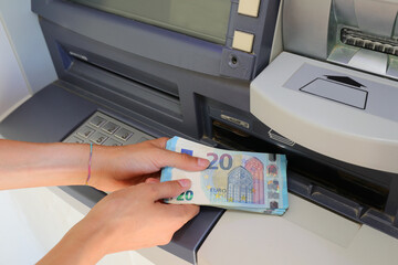hand picking up money in European banknotes from an ATM bank cash machine