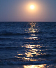circle of light in the evening and the reflection on the placid water of the ocean