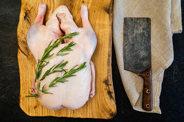 Raw whole duck, spices rosemary on a cutting board handmade oak, antique handmade cleaver, sackcloth. Top view. Space for text. Everything you need to make holiday dish. Good quality.