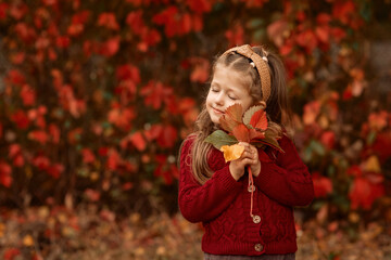 a girl with leaves in her hands in autumn park