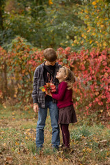 Fototapeta premium brother and sister are looking at each other and smiling in the autumn park 