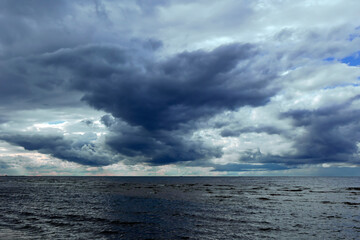 Fototapeta premium Dramatic stormy dark cloudy sky over Baltic sea just before a sea storm in Riga, Latvia. Nature environment concept. Gloomy and moody background.