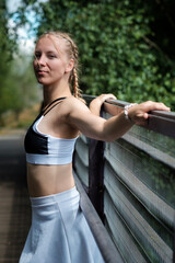 Fit caucasian young woman posing on an old walking bridge. She is holding the banister.