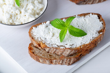 Fresh bread with carrots on a white wooden cutting board with curd cheese