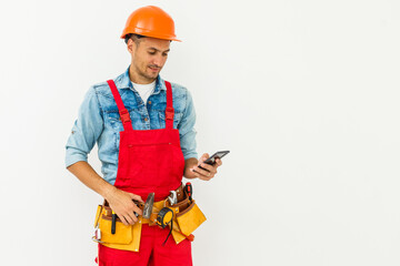 profession, construction and building - happy smiling male worker or builder in helmet and overall with smartphone over white background