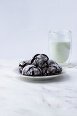 Treats on a white table. Chocolate cracks cookies and a glass of milk