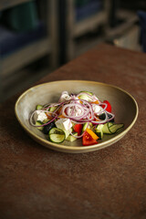 Fototapeta na wymiar Greek salad close up with feta cheese, tomatoes, olives and green leafs.