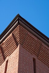 Fototapeta na wymiar Decorative red brick cornice on 19th century textile mill building set against bright blue sky